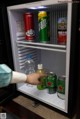 A person is opening a small refrigerator with drinks in it.